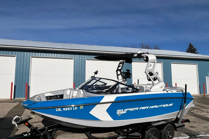 Slide: The Image of 2020 Super Air Nautique G21 boat in blue and white, parked outside a garage. - 2