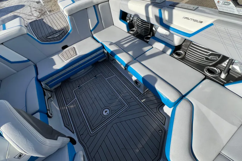 Slide: The Image of 2020 Super Air Nautique G21 interior with gray and blue seating, cup holders, and textured flooring. - 32