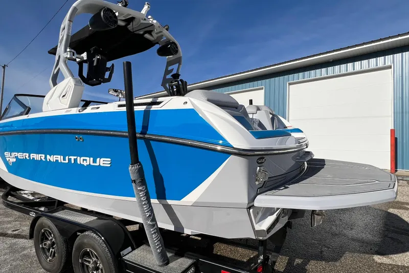 Slide: The Image of 2020 Super Air Nautique G21 boat on trailer, blue and white design, parked outside. - 7