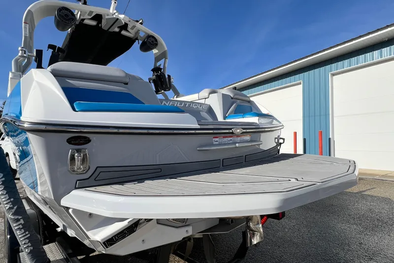 Slide: The Image of 2020 Super Air Nautique G21 boat with swim platform, parked near blue building. - 8
