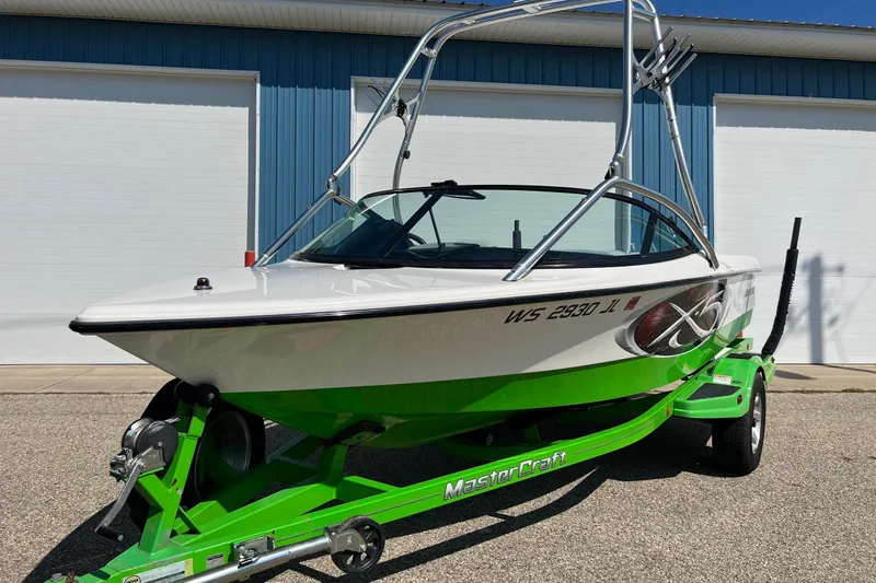 Slide: The Image of 2003 MasterCraft X-5 boat with green trailer, parked outdoors. - 11
