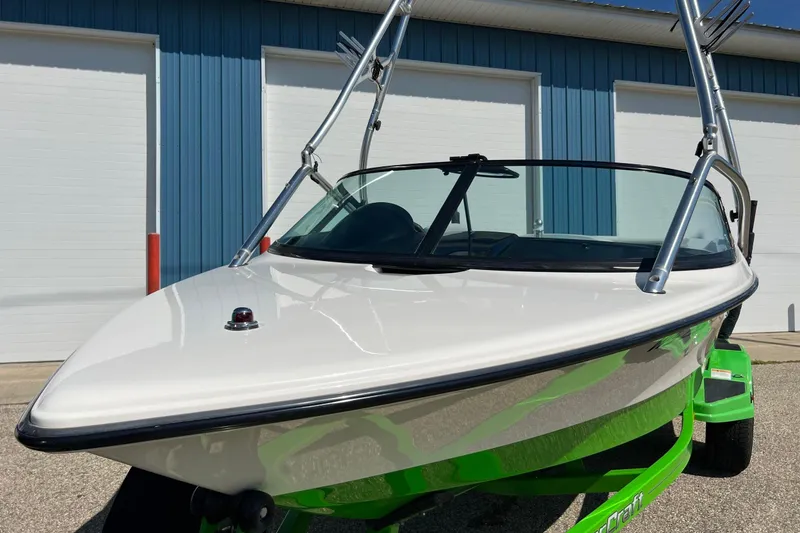 Slide: The Image of 2003 MasterCraft X-5 boat with green trailer, parked outside blue building. - 12