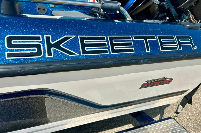 Slide: The Image of 2005 Skeeter WX1880 DC boat with Mercury engine on trailer, parked outside blue building. - 28