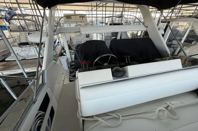 Slide: The Image of 1993 Carver 390 Cockpit Motor Yacht interior view with covered helm and marina backdrop. - 12
