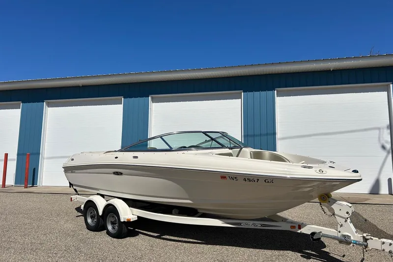 The Image of 2005 Sea Ray 200 Sport boat on trailer, parked outside blue storage facility. - 1
