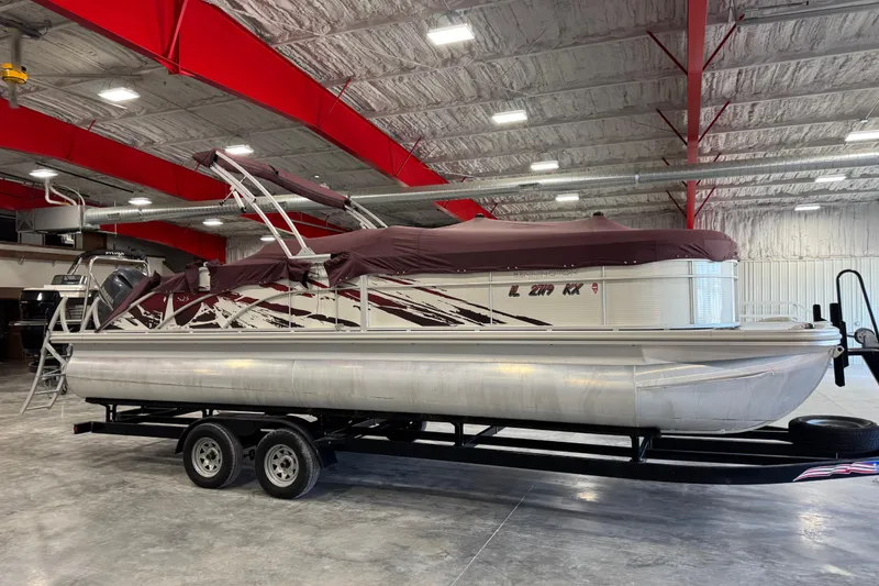 Slide: The Image of 2018 Bennington S 25 pontoon boat with cover, parked indoors on a trailer. - 21