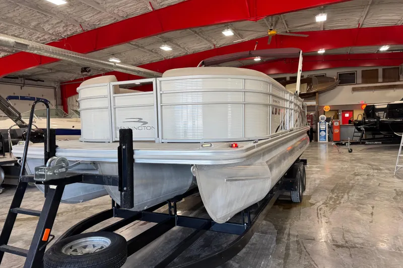 Slide: The Image of 2018 Bennington S 25 pontoon boat in a showroom with red ceiling beams. - 5