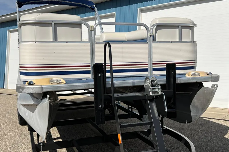 Slide: The Image of 2003 Sylvan 824 Mirage Cruise pontoon boat on trailer, parked near blue building. - 3