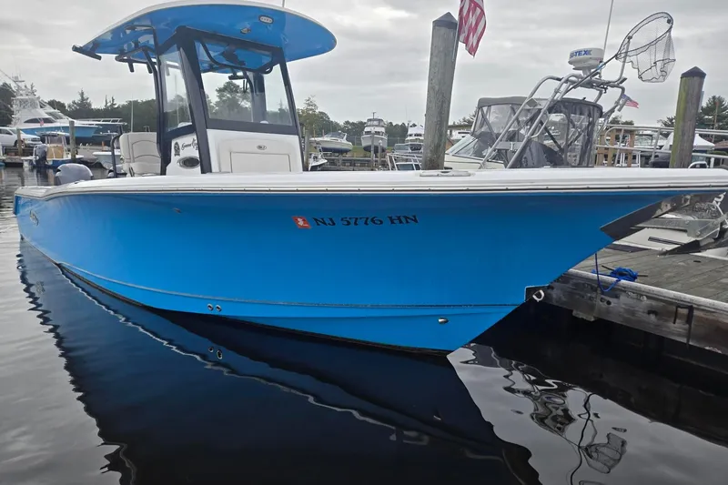 Slide: The Image of 2021 Sea Hunt Gamefish 25 boat docked in marina, vibrant blue hull. - 1