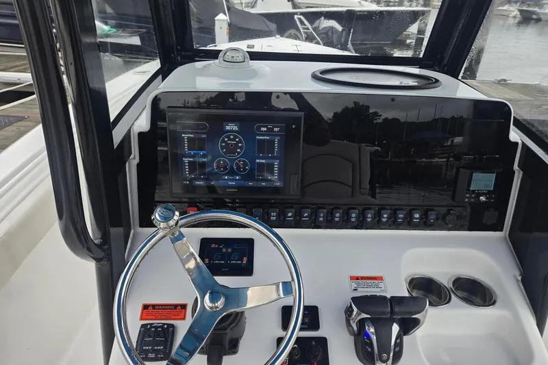 Slide: The Image of 2021 Sea Hunt Gamefish 25 dashboard with steering wheel and electronic controls. - 13