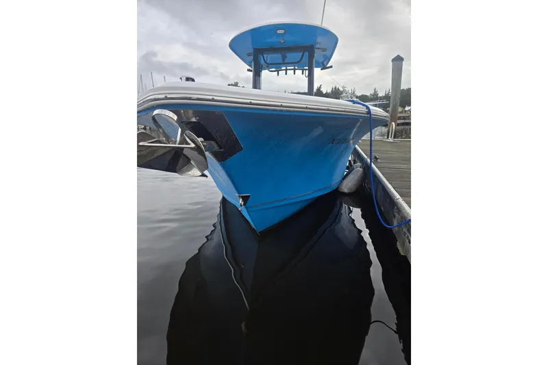 Slide: The Image of 2021 Sea Hunt Gamefish 25 boat docked, blue hull, calm water reflection. - 6