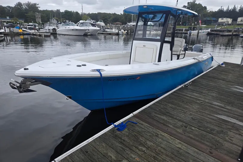 Slide: The Image of 2021 Sea Hunt Gamefish 25 boat docked at marina, blue hull, calm water background. - 7