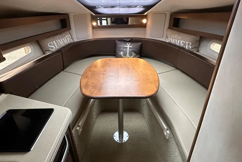 Slide: The Image of 2014 Sea Ray 280 Sundancer cabin interior with dining table and cushioned seating. - 15