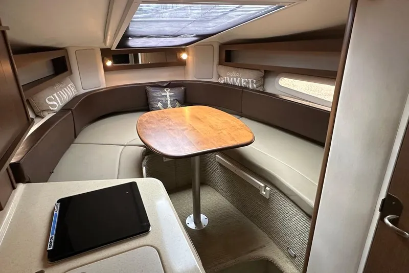 Slide: The Image of 2014 Sea Ray 280 Sundancer cabin with cozy seating and wooden table. - 16