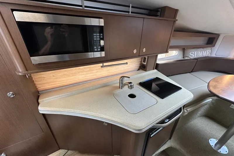 Slide: The Image of 2014 Sea Ray 280 Sundancer interior with kitchenette, microwave, sink, and seating area. - 17