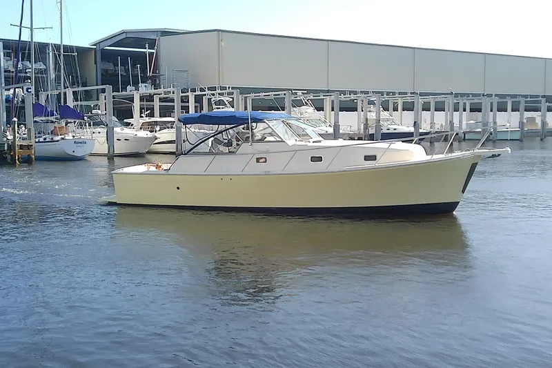 Slide: The Image of 2004 Mainship 34 Pilot II yacht docked at marina with sailboats in background. - 1