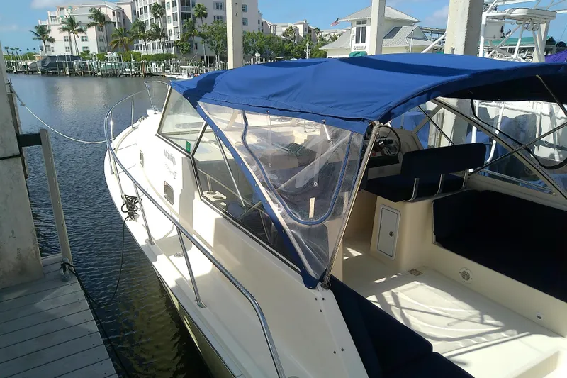 Slide: The Image of 2004 Mainship 34 Pilot II docked, featuring blue canopy and spacious interior. - 11