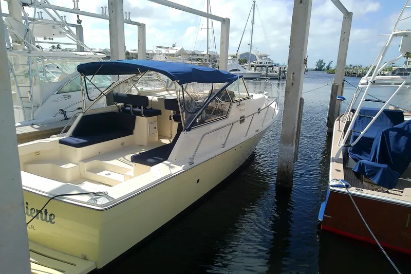Slide: The Image of 2004 Mainship 34 Pilot II docked at marina, featuring blue canopy and spacious seating. - 12