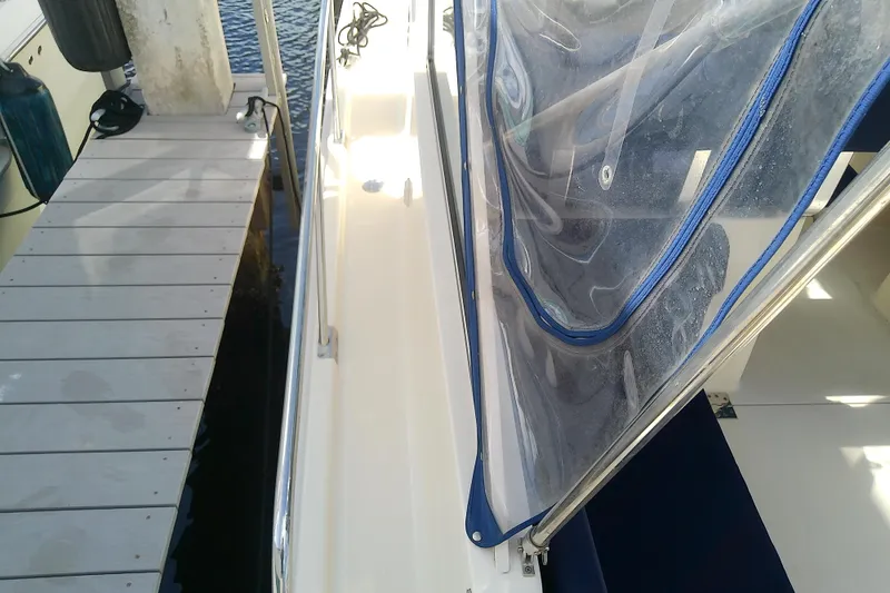 Slide: The Image of 2004 Mainship 34 Pilot II docked, featuring clear canopy and white deck. - 26