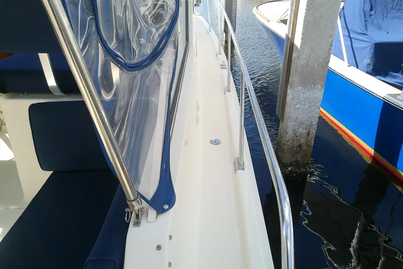 Slide: The Image of 2004 Mainship 34 Pilot II boat docked, featuring blue seating and clear canopy. - 28