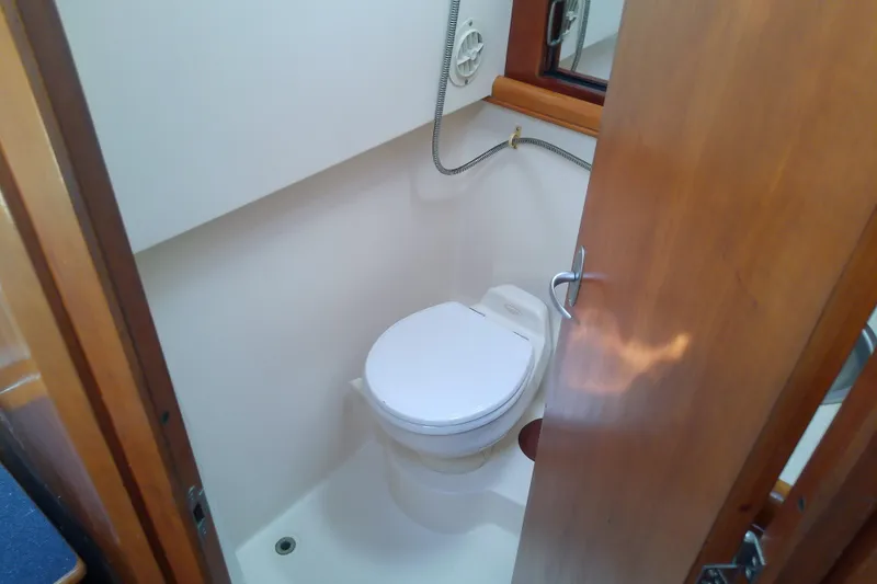 Slide: The Image of 2004 Mainship 34 Pilot II boat bathroom with toilet and wooden door. - 38