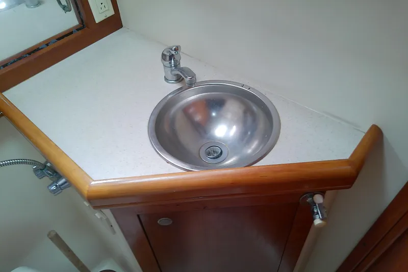 Slide: The Image of 2004 Mainship 34 Pilot II boat bathroom sink with wooden trim and modern faucet. - 39