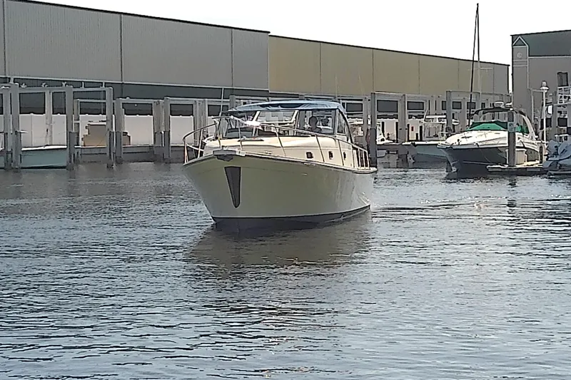 Slide: The Image of 2004 Mainship 34 Pilot II yacht docked at marina, surrounded by water and other boats. - 5