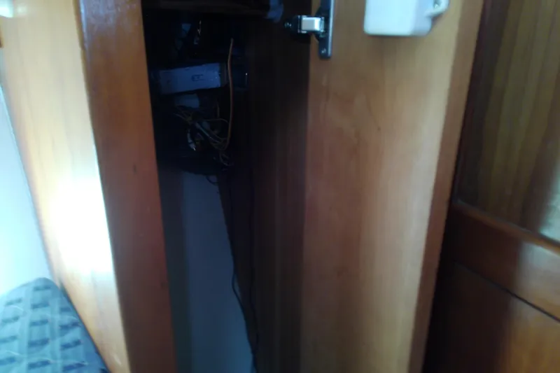 Slide: The Image of Open wooden cabinet on 2004 Mainship 34 Pilot II boat, revealing interior wiring. - 58