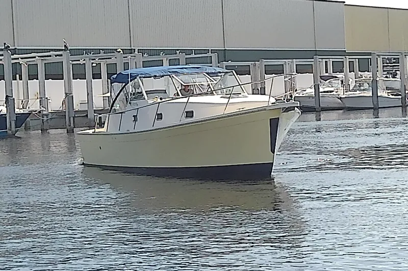 Slide: The Image of 2004 Mainship 34 Pilot II boat docked in marina, featuring a blue canopy. - 6