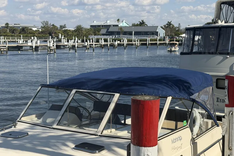 Slide: The Image of 2004 Mainship Pilot 34 Sedan docked at marina with blue canopy. - 77
