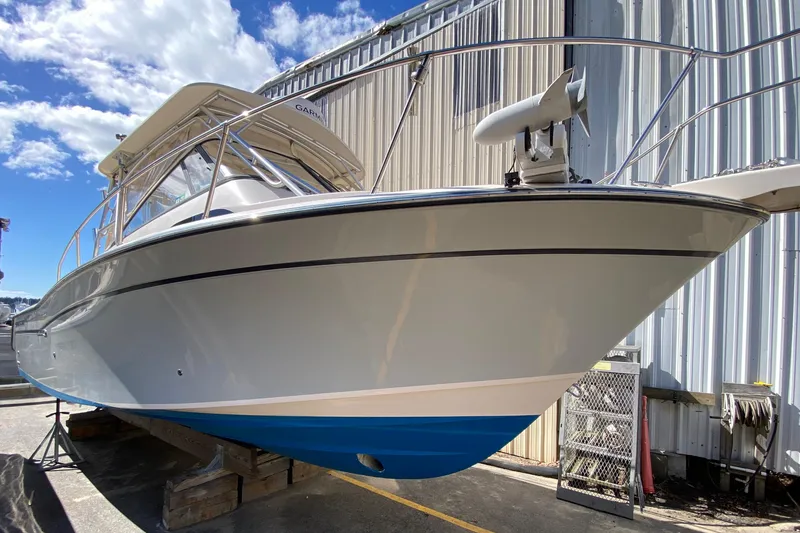 Slide: The Image of 2017 Grady-White Marlin 300 boat with blue hull, docked outdoors under a clear sky. - 0
