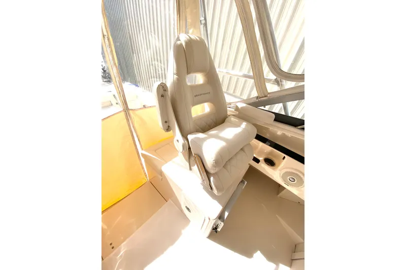 Slide: The Image of Captain's chair on 2017 Grady-White Marlin 300 boat, featuring beige upholstery and helm controls. - 12
