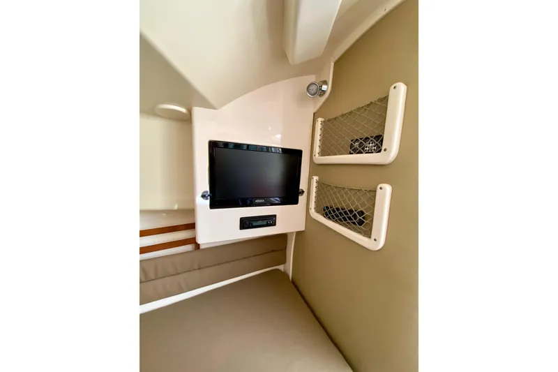 Slide: The Image of 2017 Grady-White Marlin 300 cabin interior with TV and storage nets. - 18