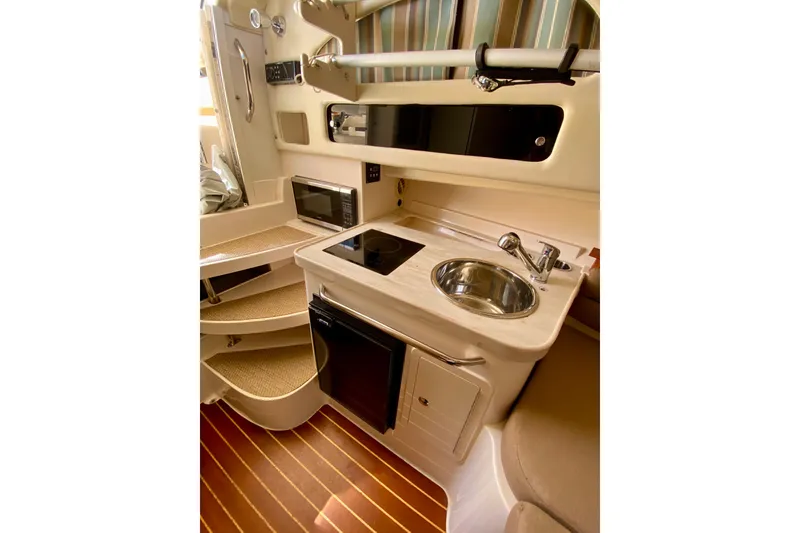 Slide: The Image of 2017 Grady-White Marlin 300 cabin interior with kitchenette, featuring sink, stove, and microwave. - 19