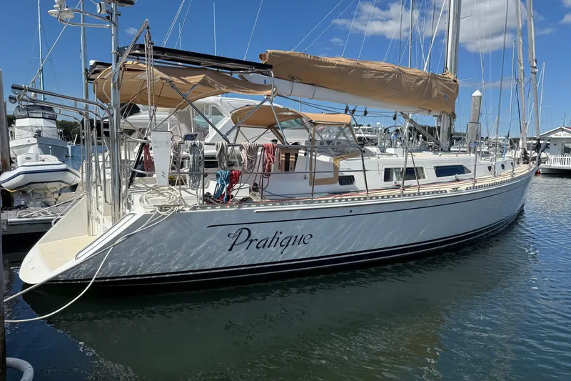 The Image of Outbound 46 sailboat from 2012 docked at a marina, featuring tan sails and sleek design. - 1