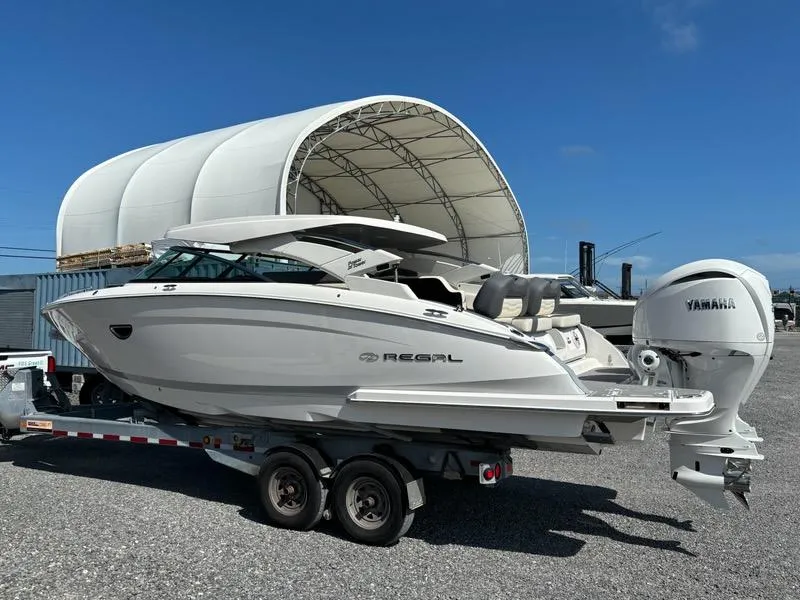 Slide: The Image of 2025 Regal LX9 boat on trailer, parked near a large white canopy. - 4