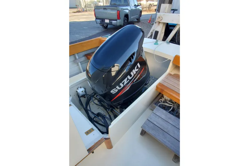 Slide: The Image of Suzuki outboard motor on 2016 First Light Monomoy 26 boat, parked near a truck. - 15