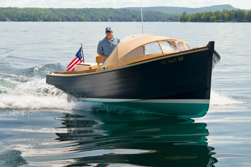 Slide: The Image of 2016 First Light Monomoy 26 boat cruising on a calm lake with American flag. - 1