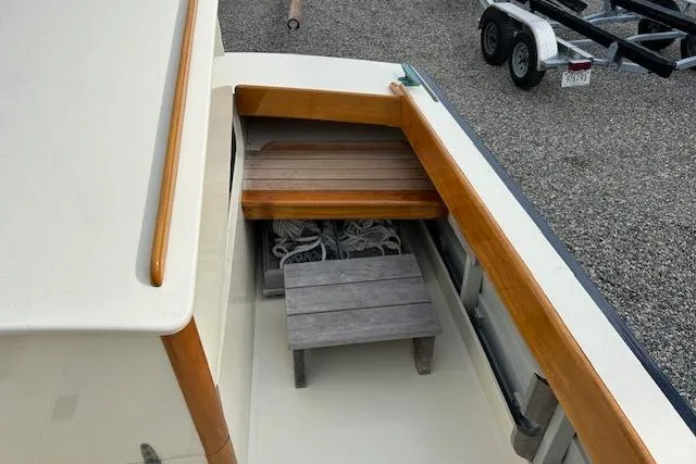 Slide: The Image of 2016 First Light Monomoy 26 boat deck with wooden seating and storage area. - 7
