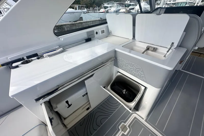 Slide: The Image of 2025 Regal LX36 yacht interior with open storage compartments and sink, docked at marina. - 19
