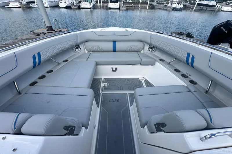 Slide: The Image of 2025 Regal LX36 boat interior with spacious seating and modern design at a marina. - 23