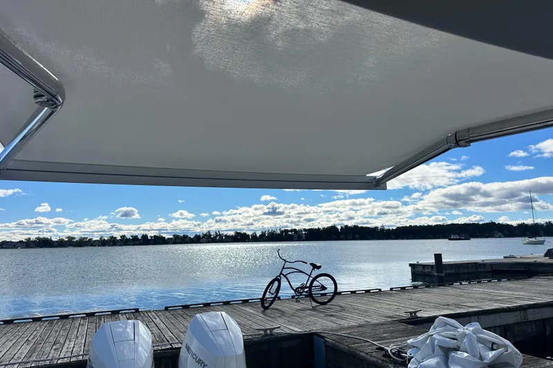 Slide: The Image of Boat dock view with bicycle, under Regal LX36 awning, serene lake and cloudy sky, 2025. - 32
