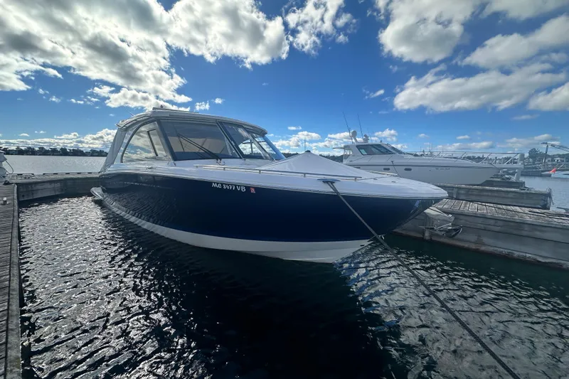 Slide: The Image of 2025 Regal LX36 boat docked on a sunny day with blue sky and clouds. - 5