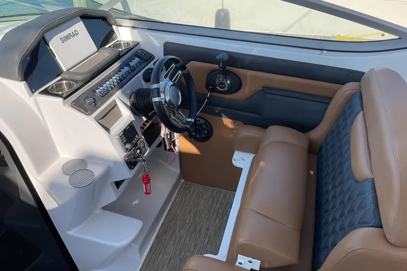 Slide: The Image of 2019 Rinker 290 Express Cruiser helm with brown seating and modern controls. - 11