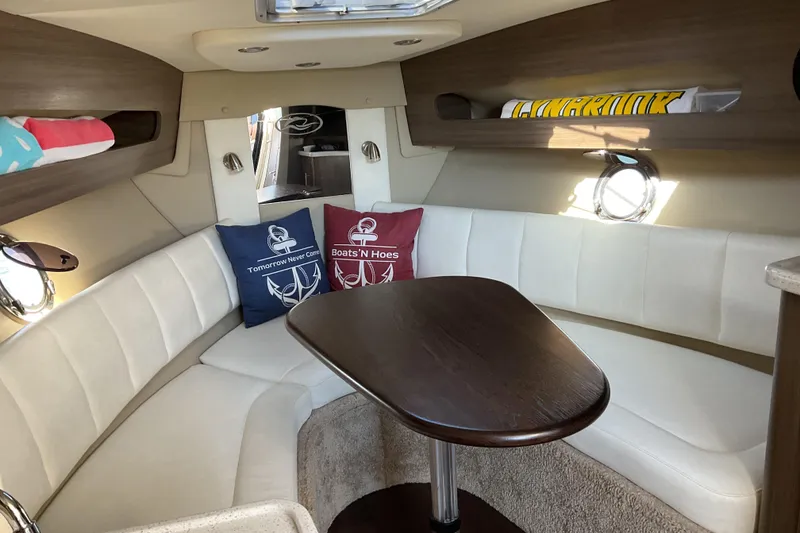 Slide: The Image of 2019 Rinker 290 Express Cruiser cabin with white seating and decorative pillows. - 13