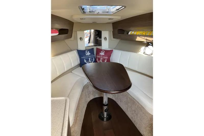 Slide: The Image of 2019 Rinker 290 Express Cruiser interior with cozy seating and wooden table. - 14