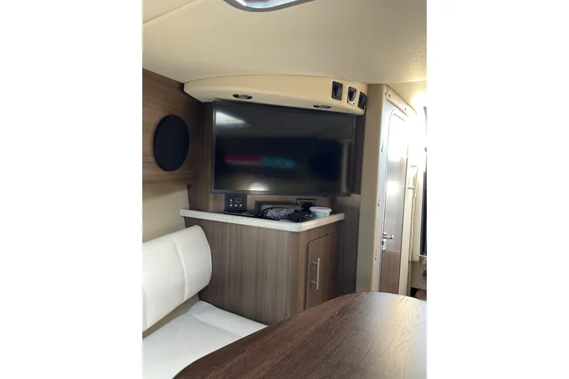 Slide: The Image of 2019 Rinker 290 Express Cruiser interior with TV and seating area. - 17