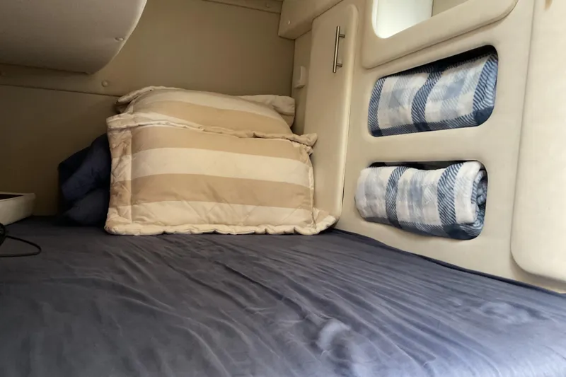 Slide: The Image of Cozy cabin interior of 2019 Rinker 290 Express Cruiser with pillows and rolled blankets. - 18