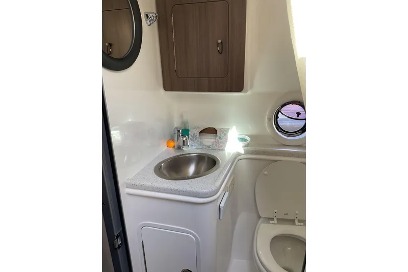 Slide: The Image of 2019 Rinker 290 Express Cruiser bathroom with sink, toilet, and storage cabinet. - 19