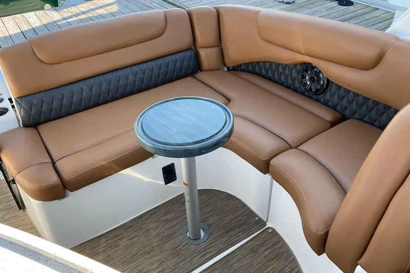 Slide: The Image of 2019 Rinker 290 Express Cruiser interior with brown seating and small round table. - 4